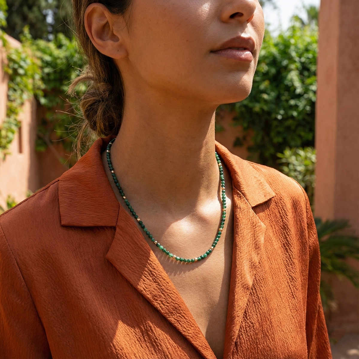 Person wearing a green beaded necklace outdoors with a blurred background