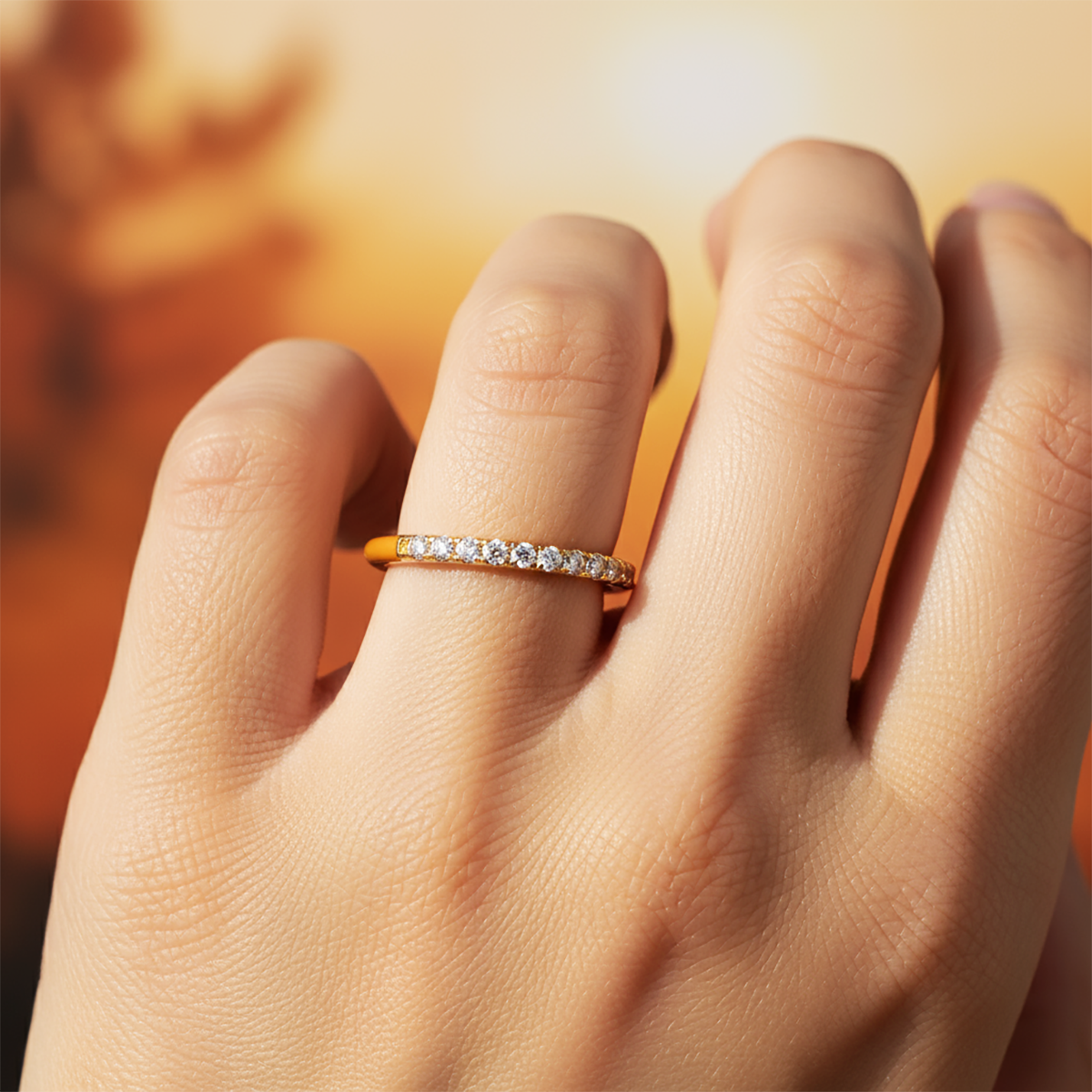 Close-up of a hand wearing a rose gold ring with small diamonds on a blurred background