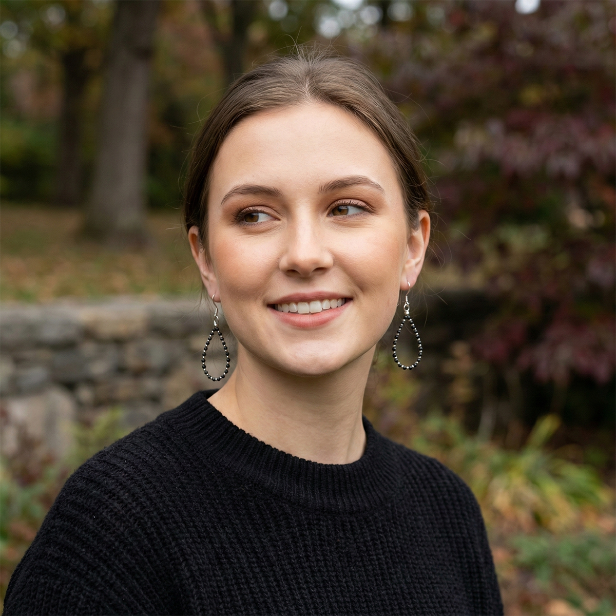 Woman wearing a black sweater with hoop earrings outdoors
