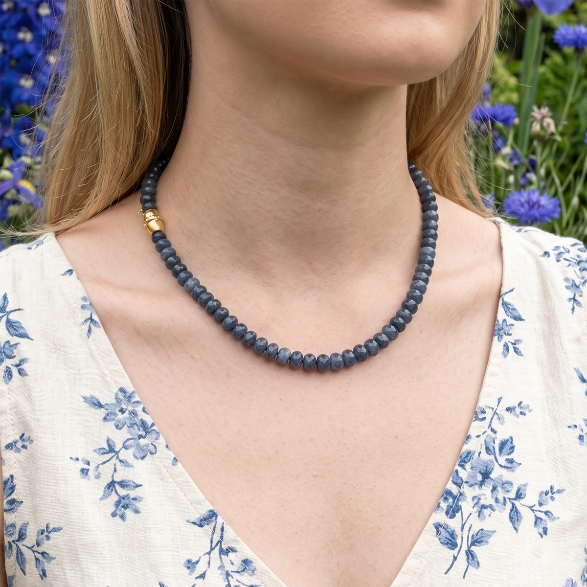 Woman wearing a blue beaded necklace with a floral background