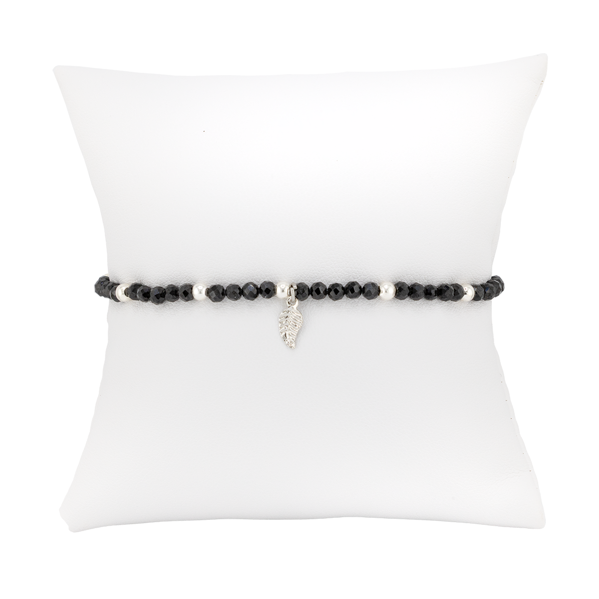 Black beaded bracelet with a silver charm on a white pillow