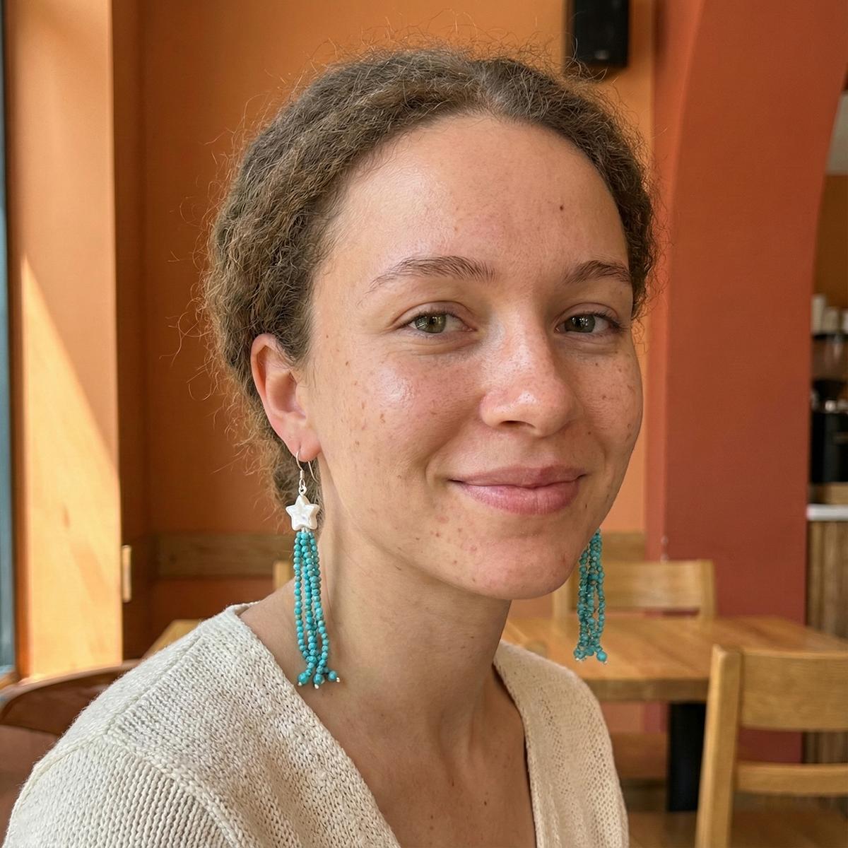 Woman with braided hair and turquoise earrings in a casual setting
