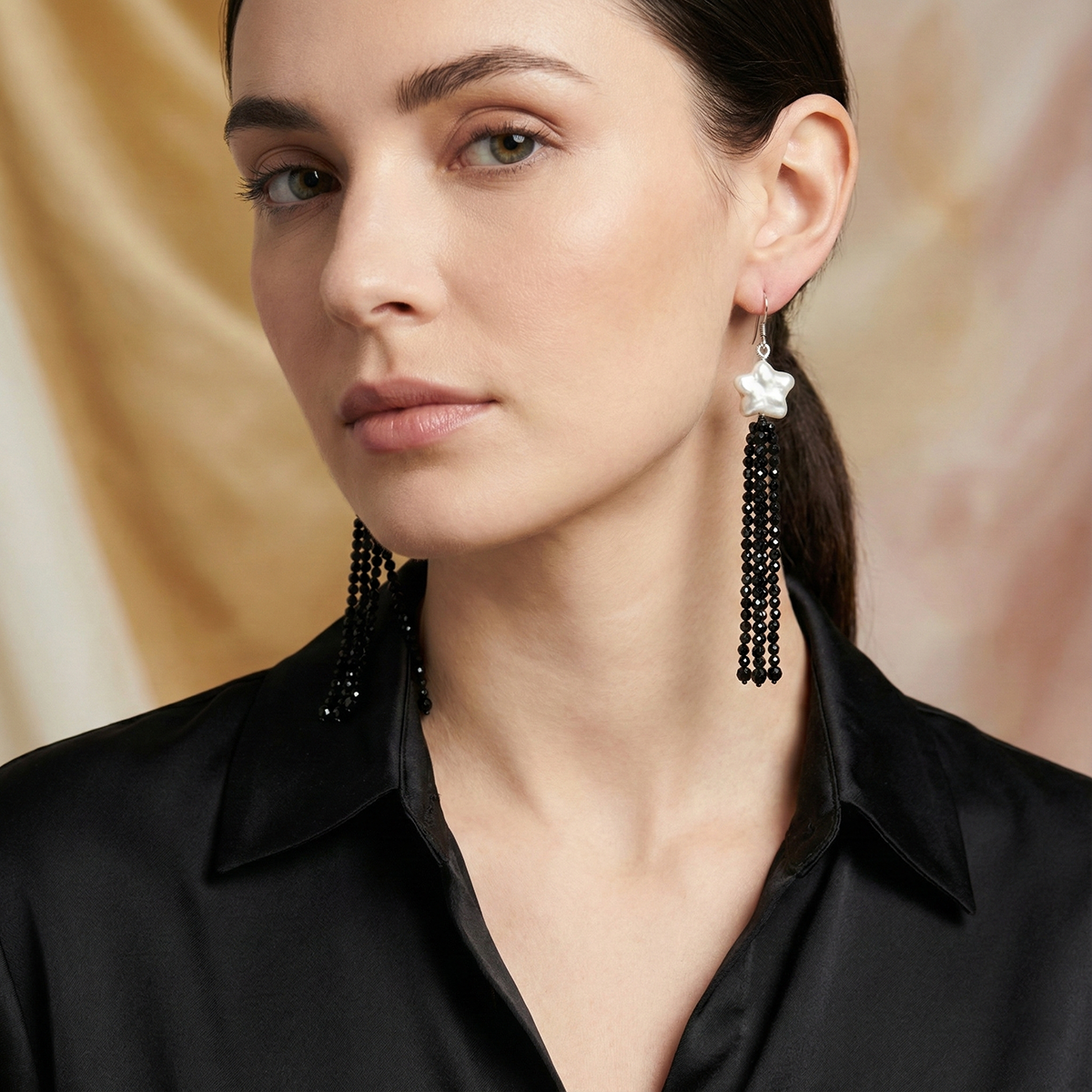 Woman wearing black tassel earrings with a neutral background
