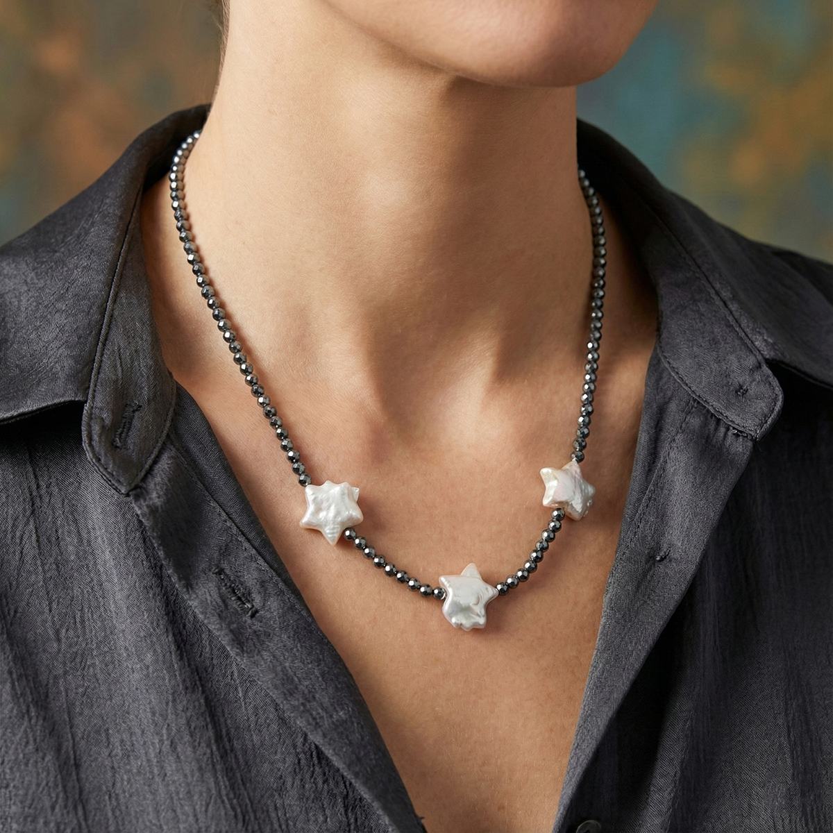 Necklace with star-shaped pendants worn by a person against a blurred background