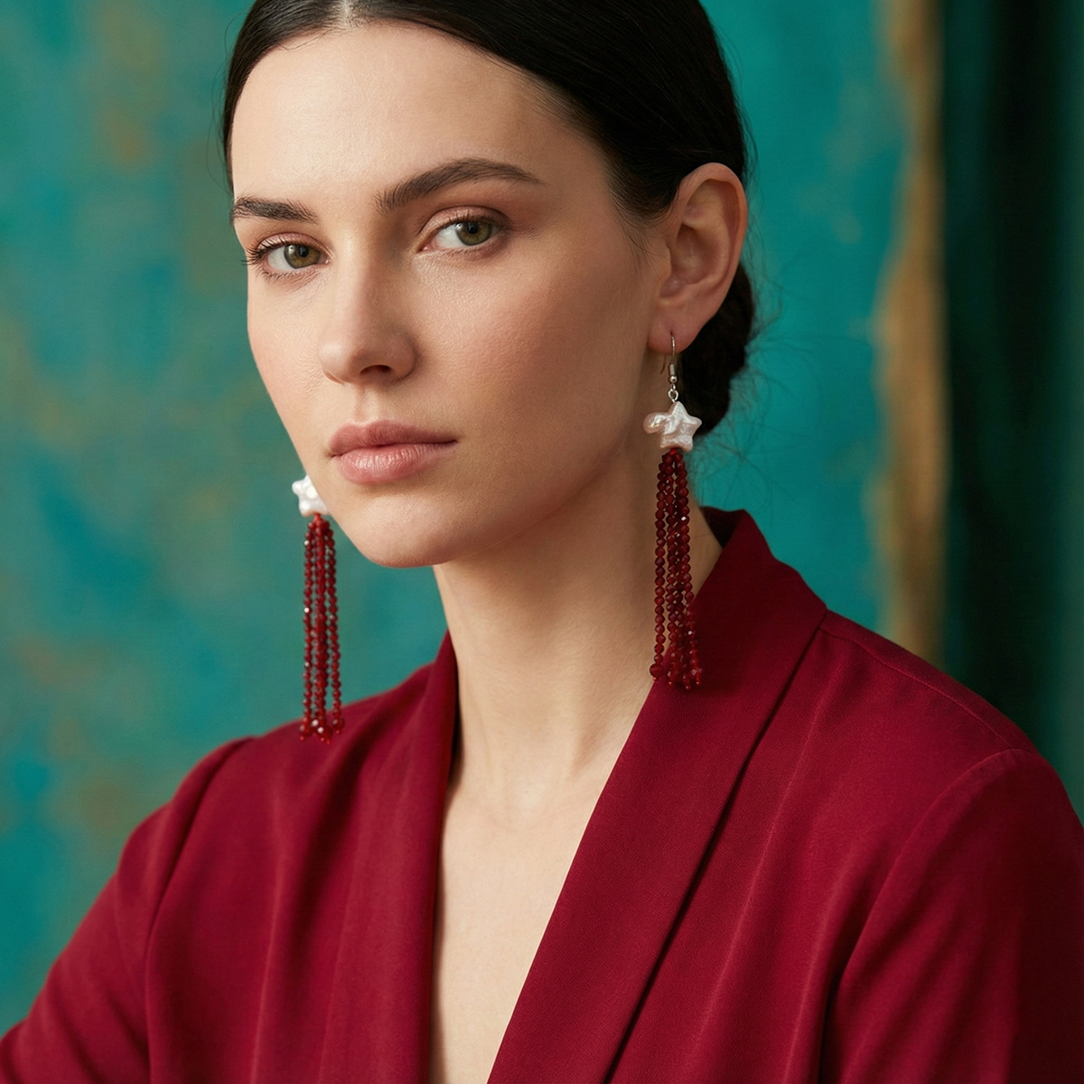 Woman wearing red earrings with a teal background