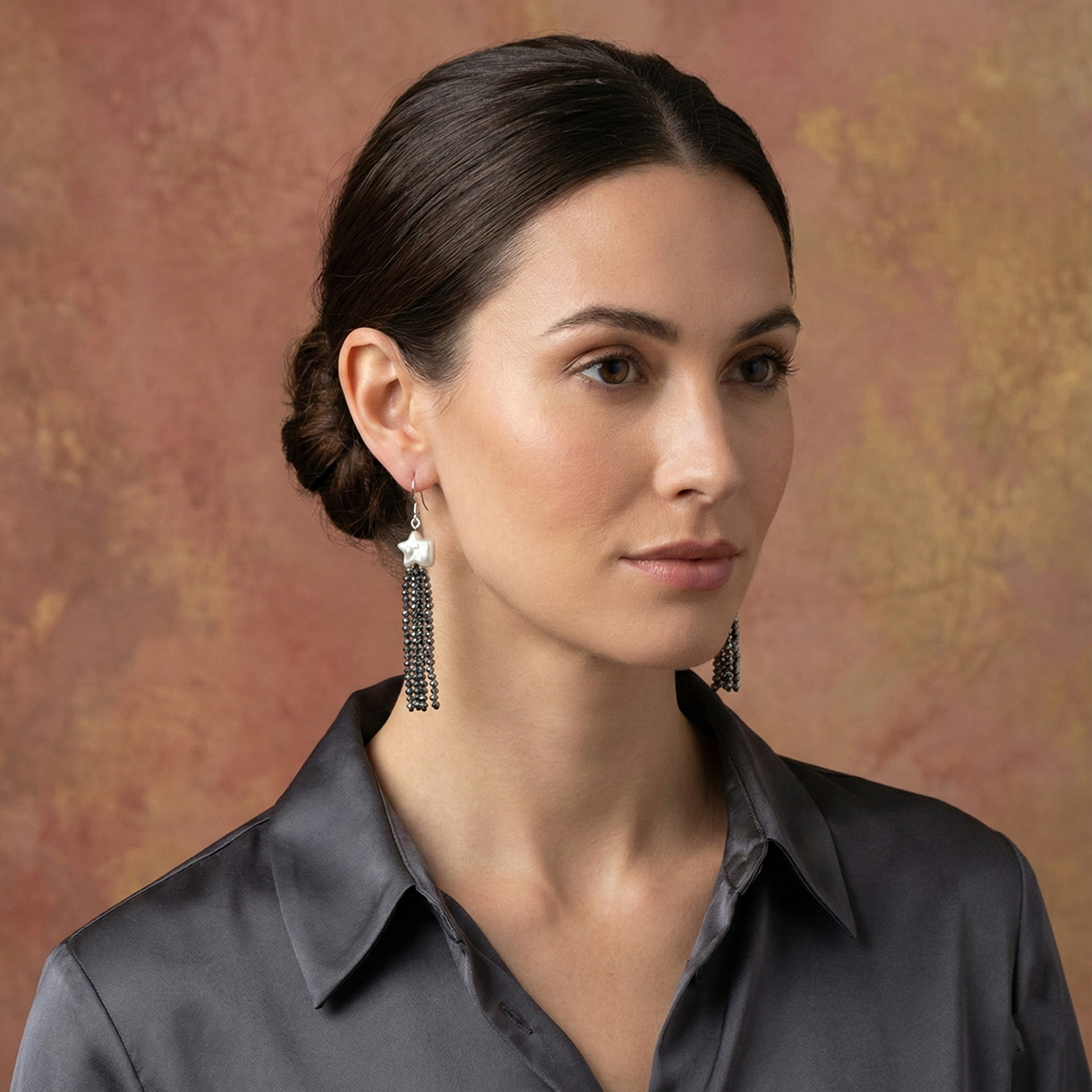 Woman wearing tassel earrings against a textured brown background