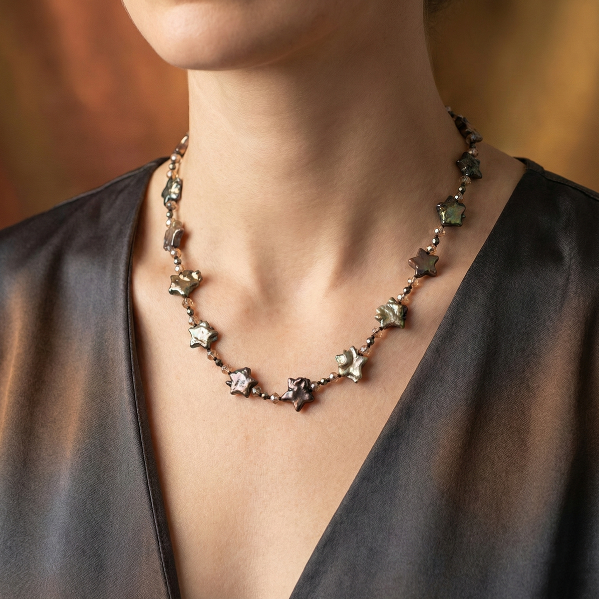 Necklace with star-shaped pendants worn by a person against a blurred background