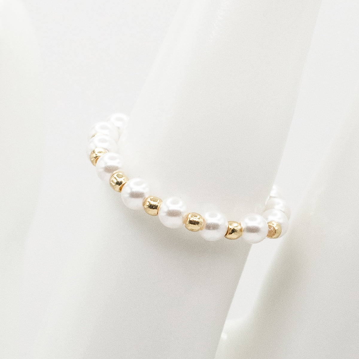 Pearl and gold beaded bracelet on a white background