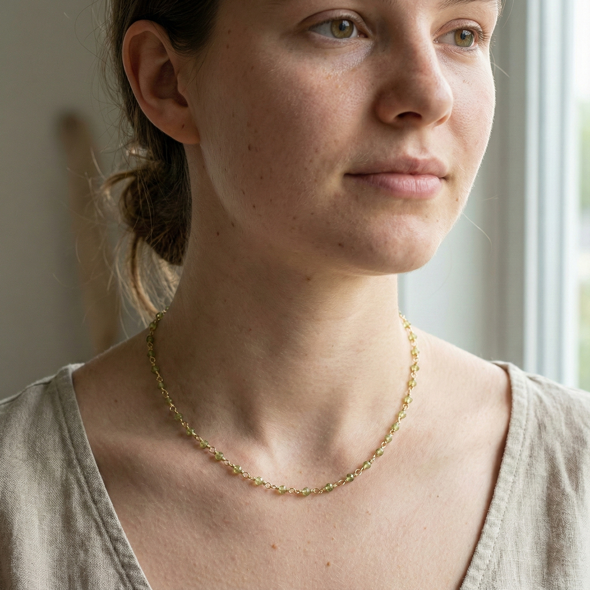Woman wearing a gold necklace in a softly lit room