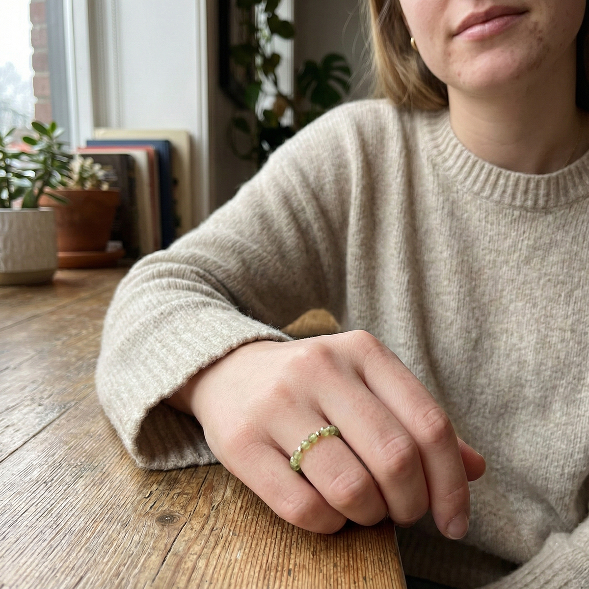 Person wearing a ring on a wooden table with a blurred background