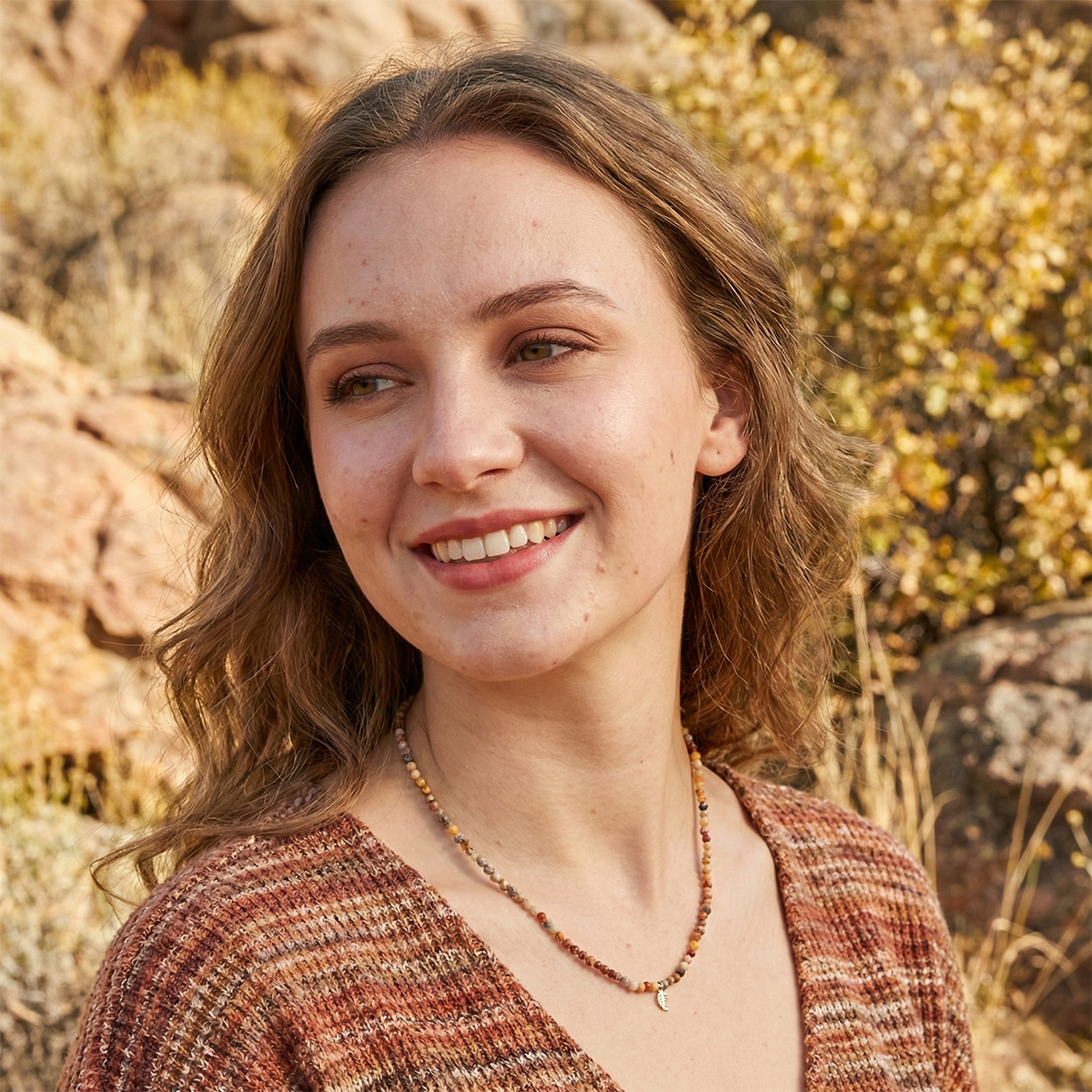 Woman with a warm smile in front of a natural rocky background