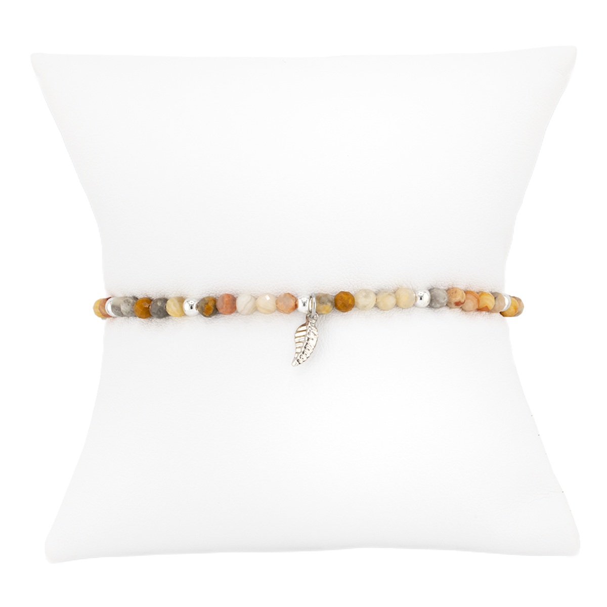 Beaded bracelet with a leaf charm on a white pillow