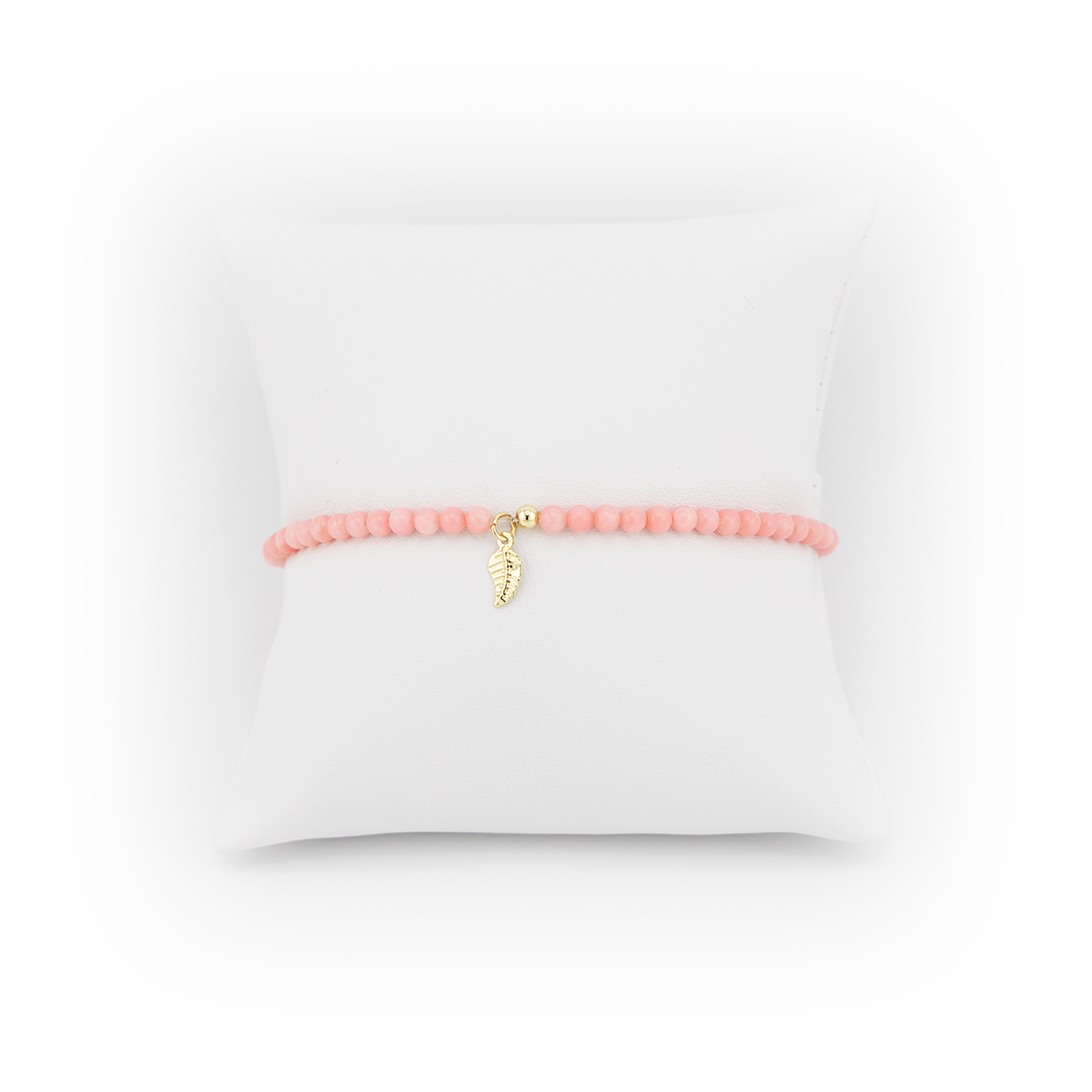 Peach beaded bracelet with a gold charm on a white background