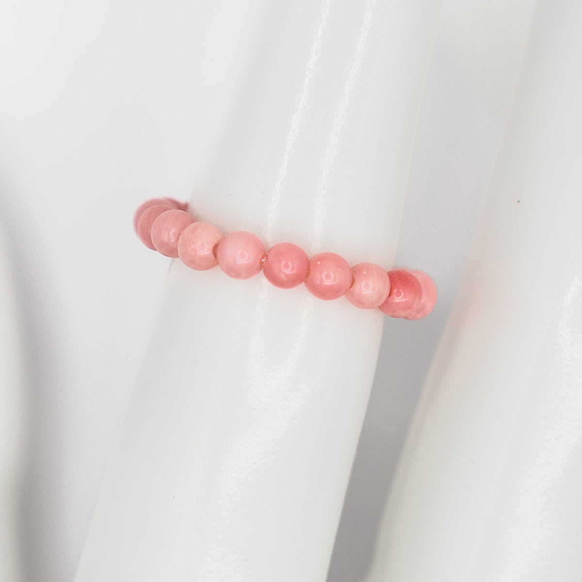 Pink beaded ring on a white fabric background