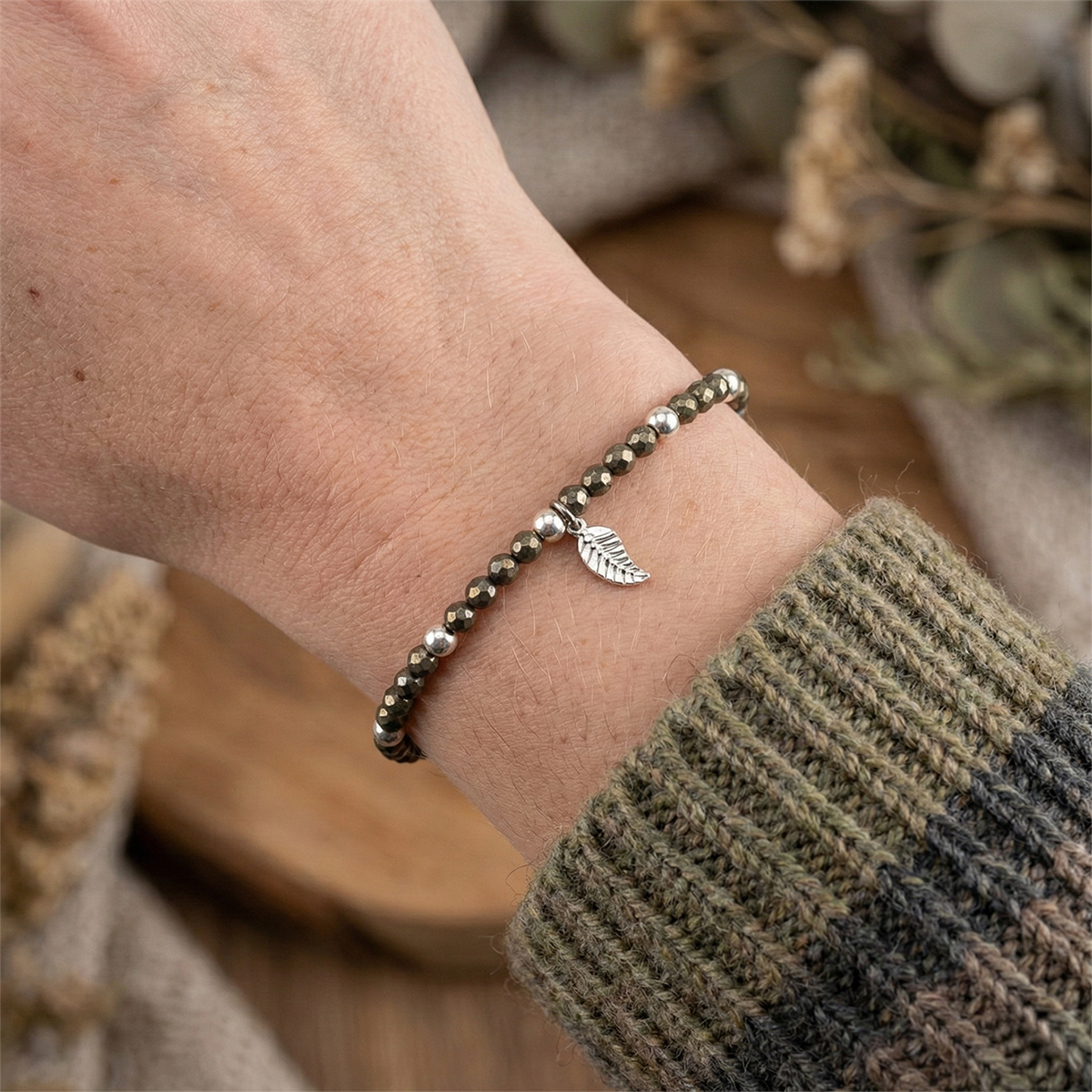Bracelet with leaf charm on a wrist, blurred natural background
