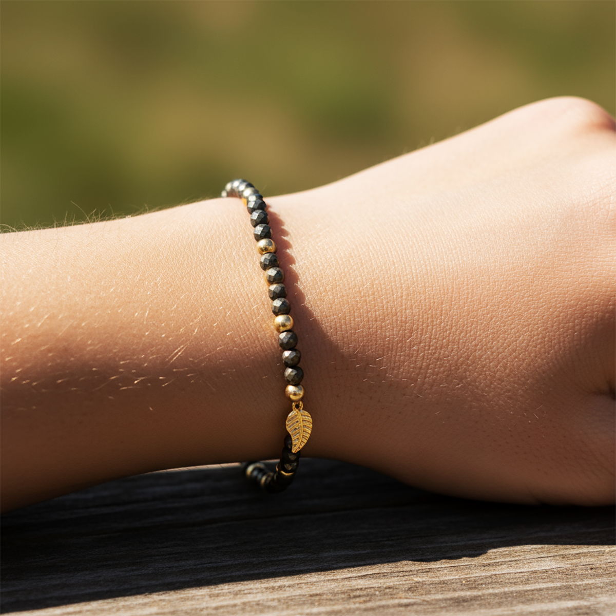 Close-up of a wrist wearing a beaded bracelet with leaf charm on a blurred natural background