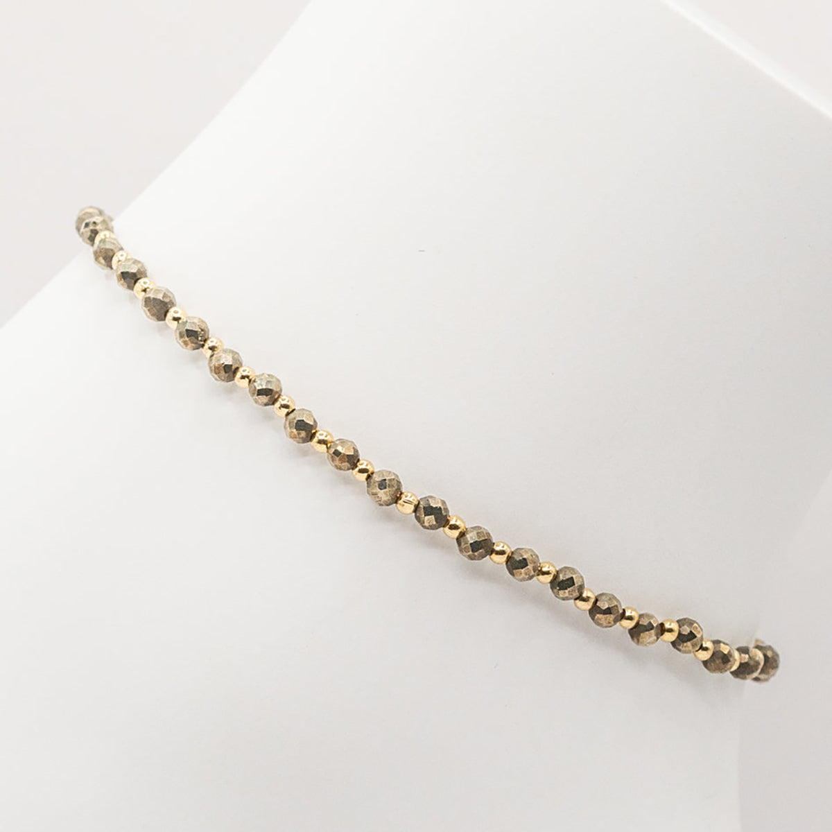 Gold beaded bracelet on a white surface