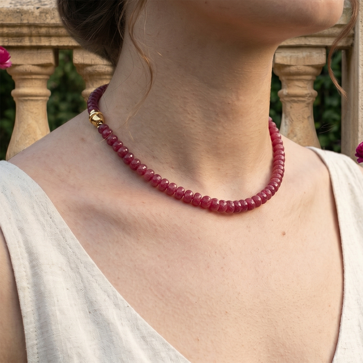 Close-up of a person wearing a red beaded necklace with a blurred background
