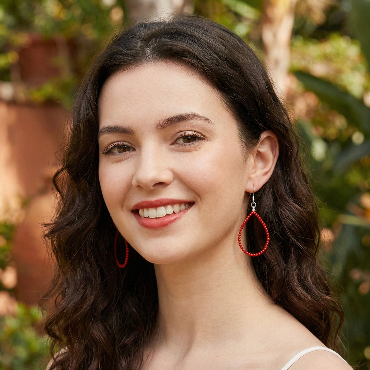 Woman wearing red hoop earrings with a blurred natural background