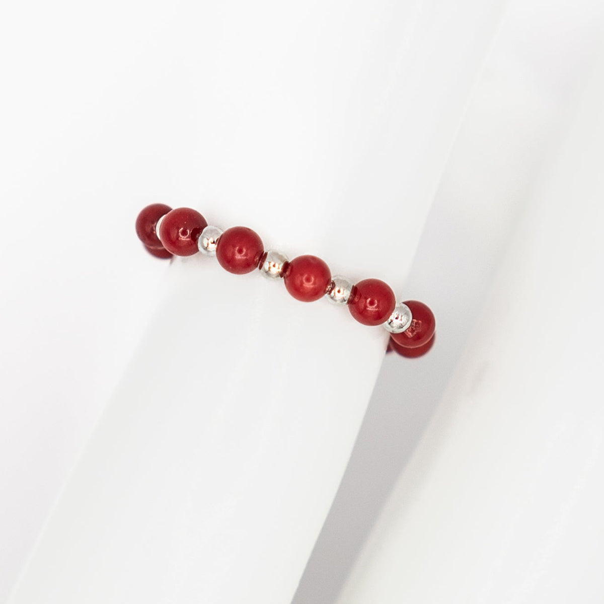 Red beaded ring with silver accents on a white background
