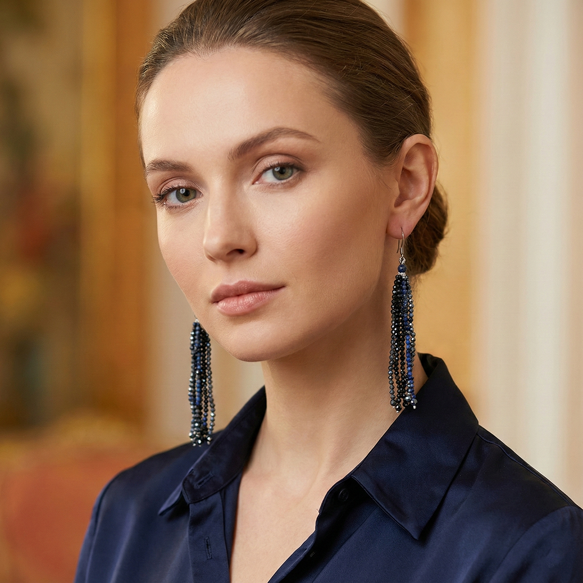 Woman wearing long, dark earrings with a blurred background