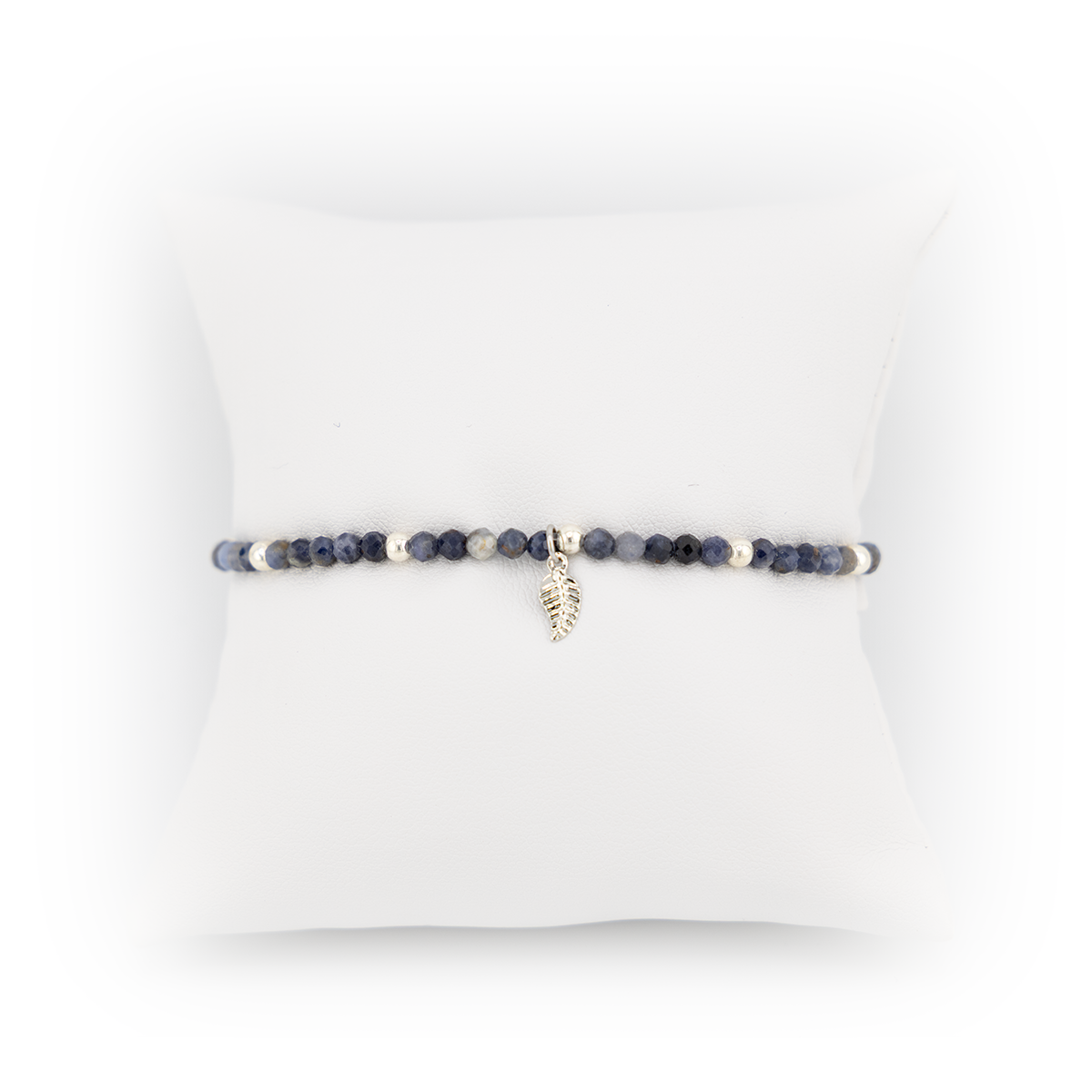 Beaded bracelet with a leaf charm on a white cushion