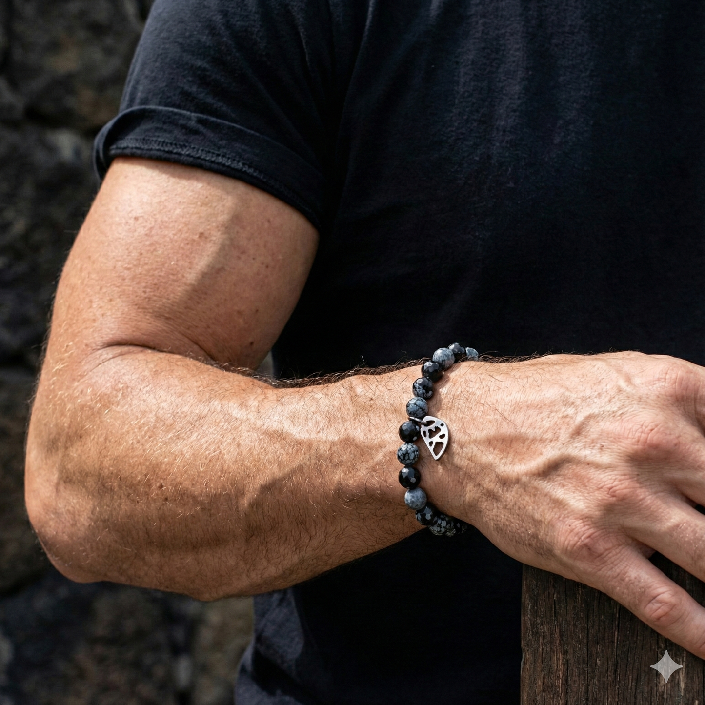 Person wearing a black beaded bracelet with a silver clasp on their wrist.