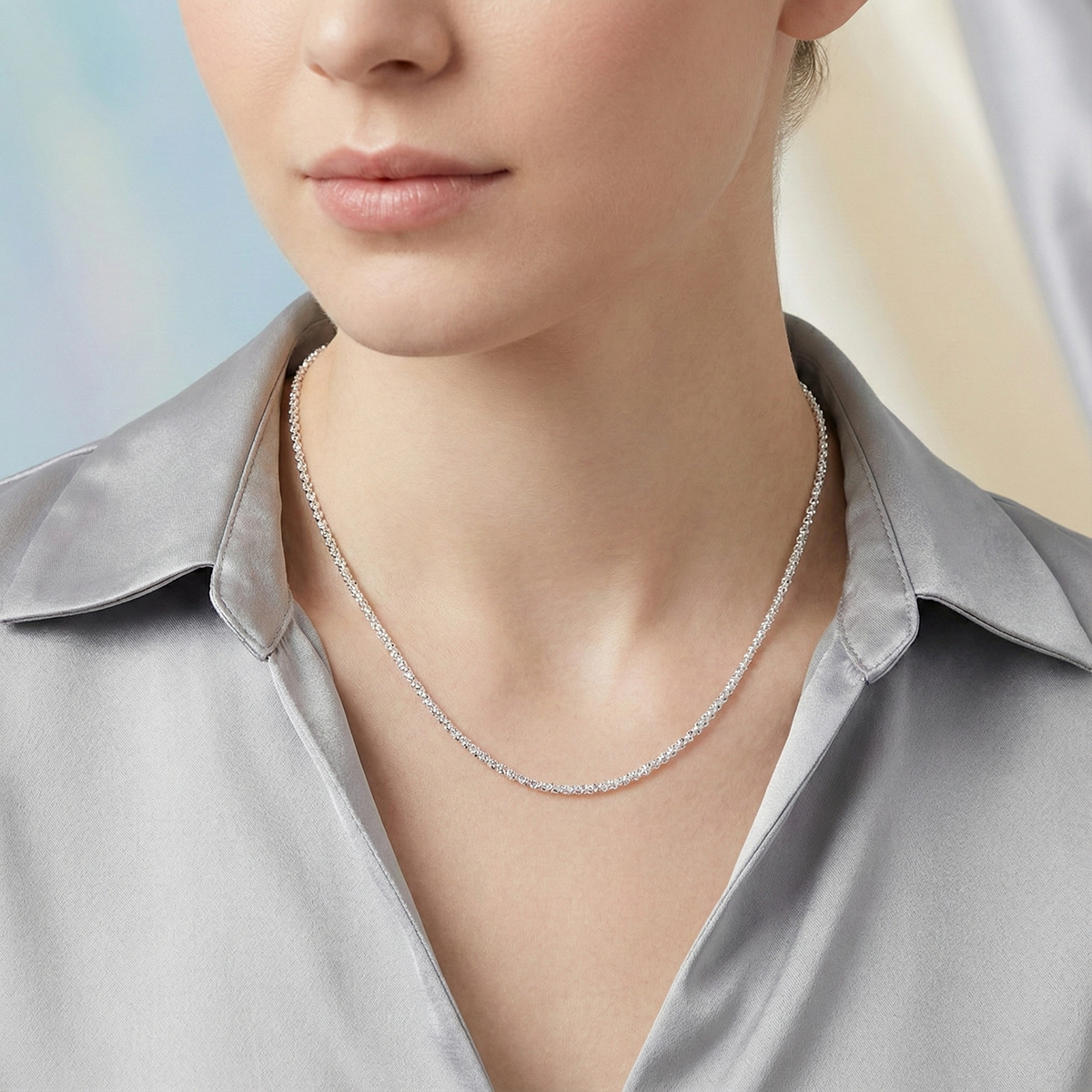 Silver necklace worn by a person with a neutral background