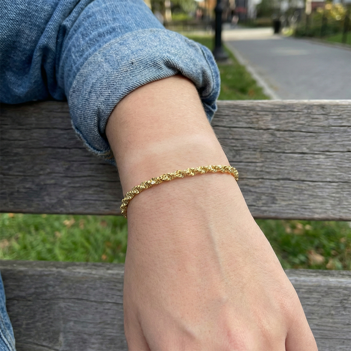 Gold bracelet on a wrist with a blurred outdoor background