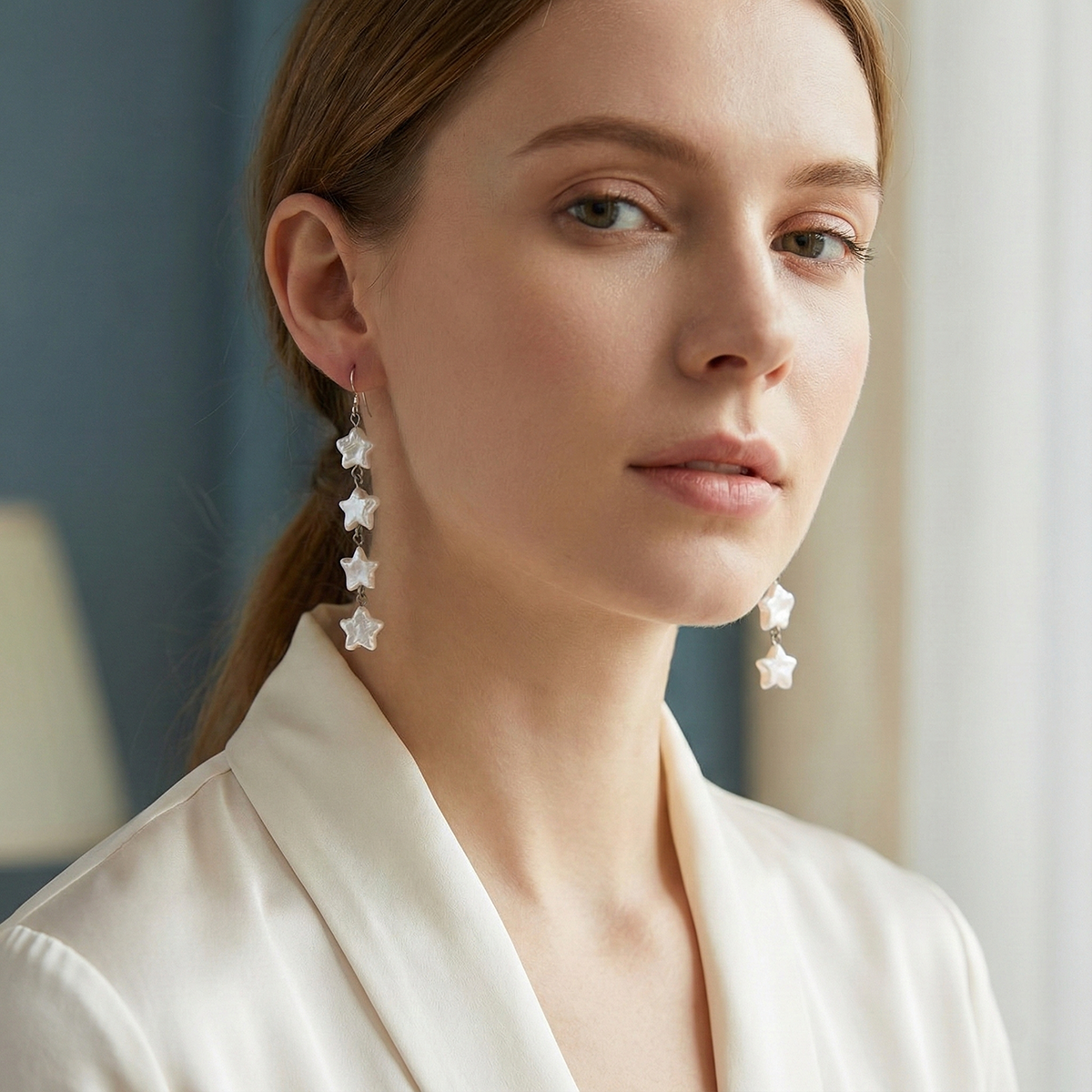 Woman wearing star-shaped earrings with a neutral background