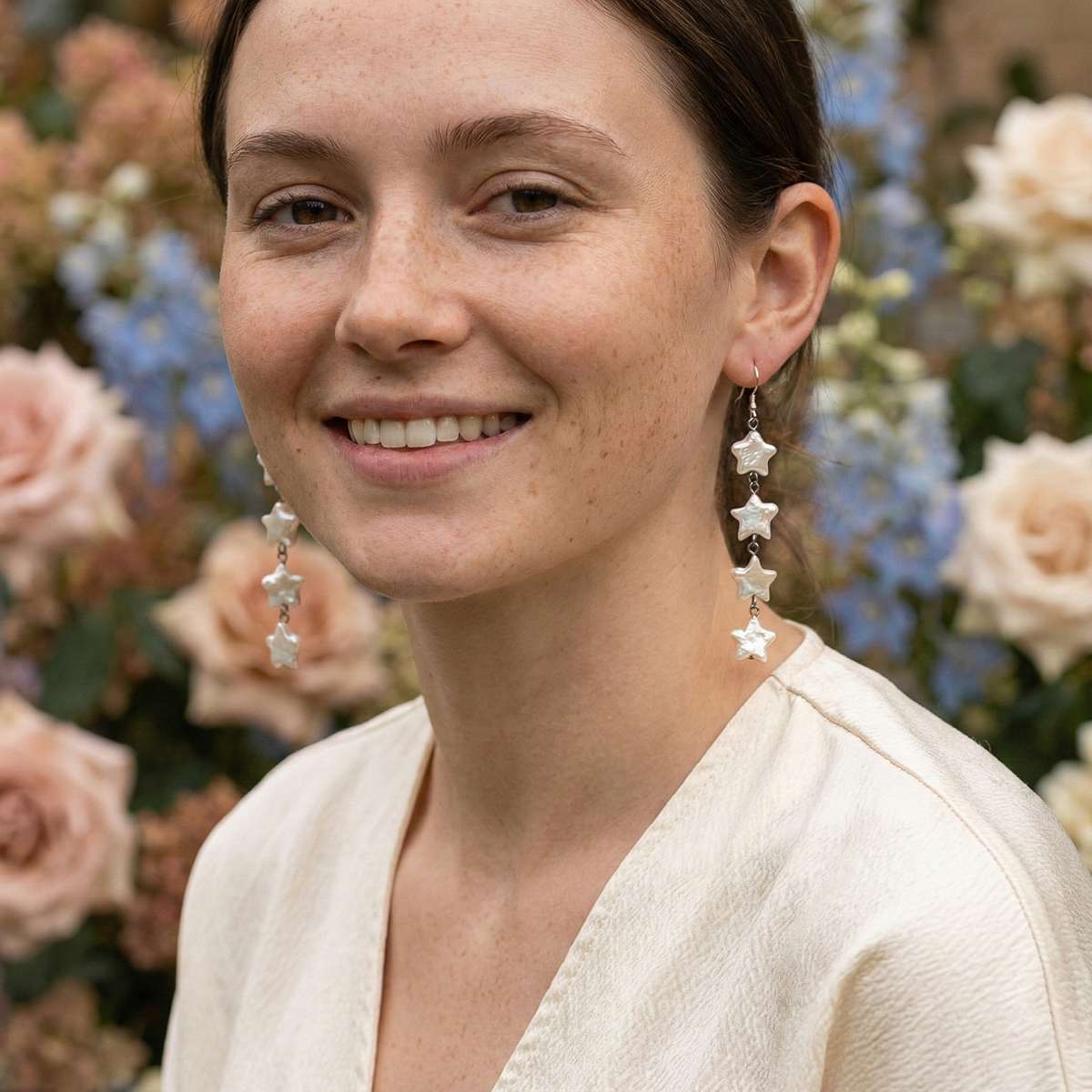 Woman wearing star-shaped earrings with a floral background
