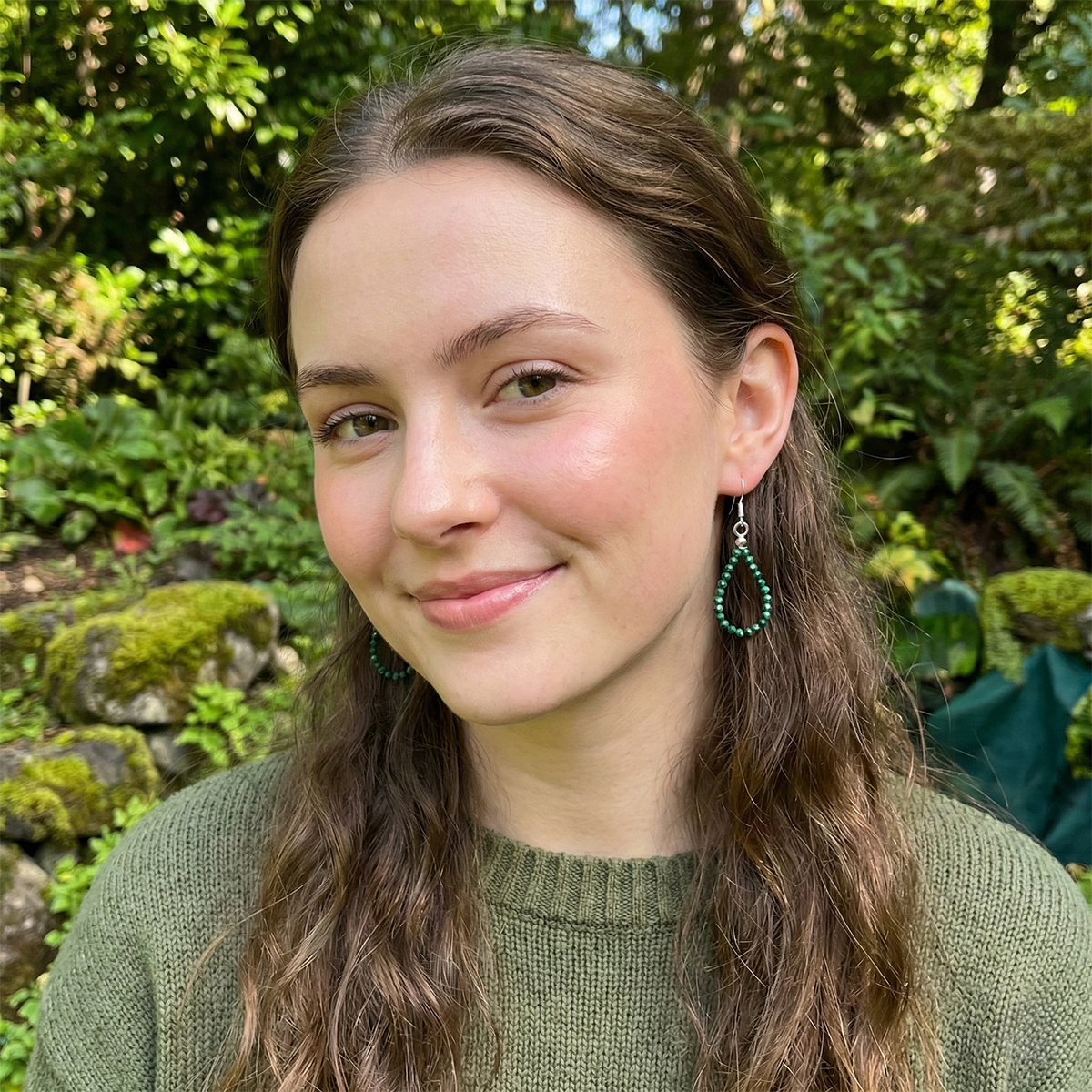Woman with green earrings standing in a garden