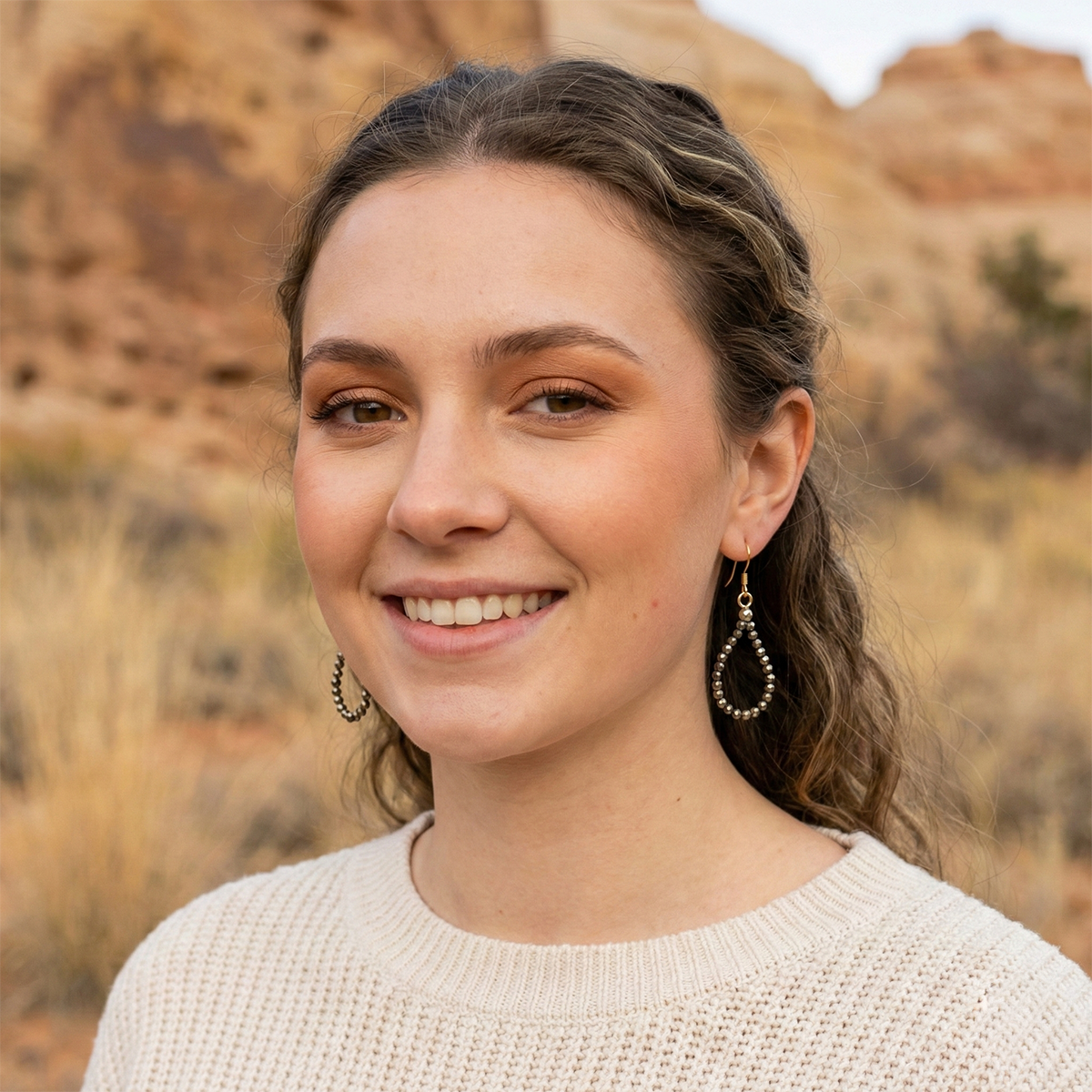 Woman with braided hair smiling outdoors with a natural background