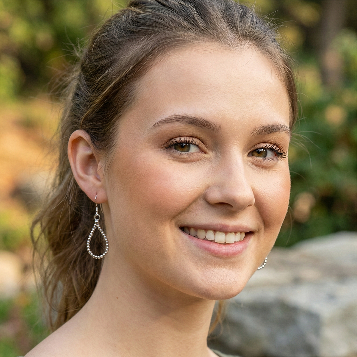 Woman with earrings smiling outdoors