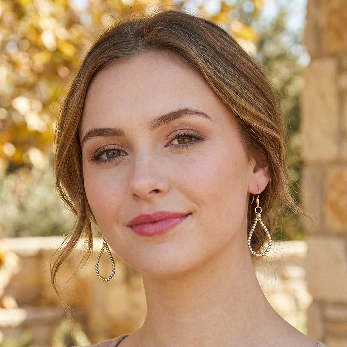 Woman wearing gold hoop earrings with a blurred natural background