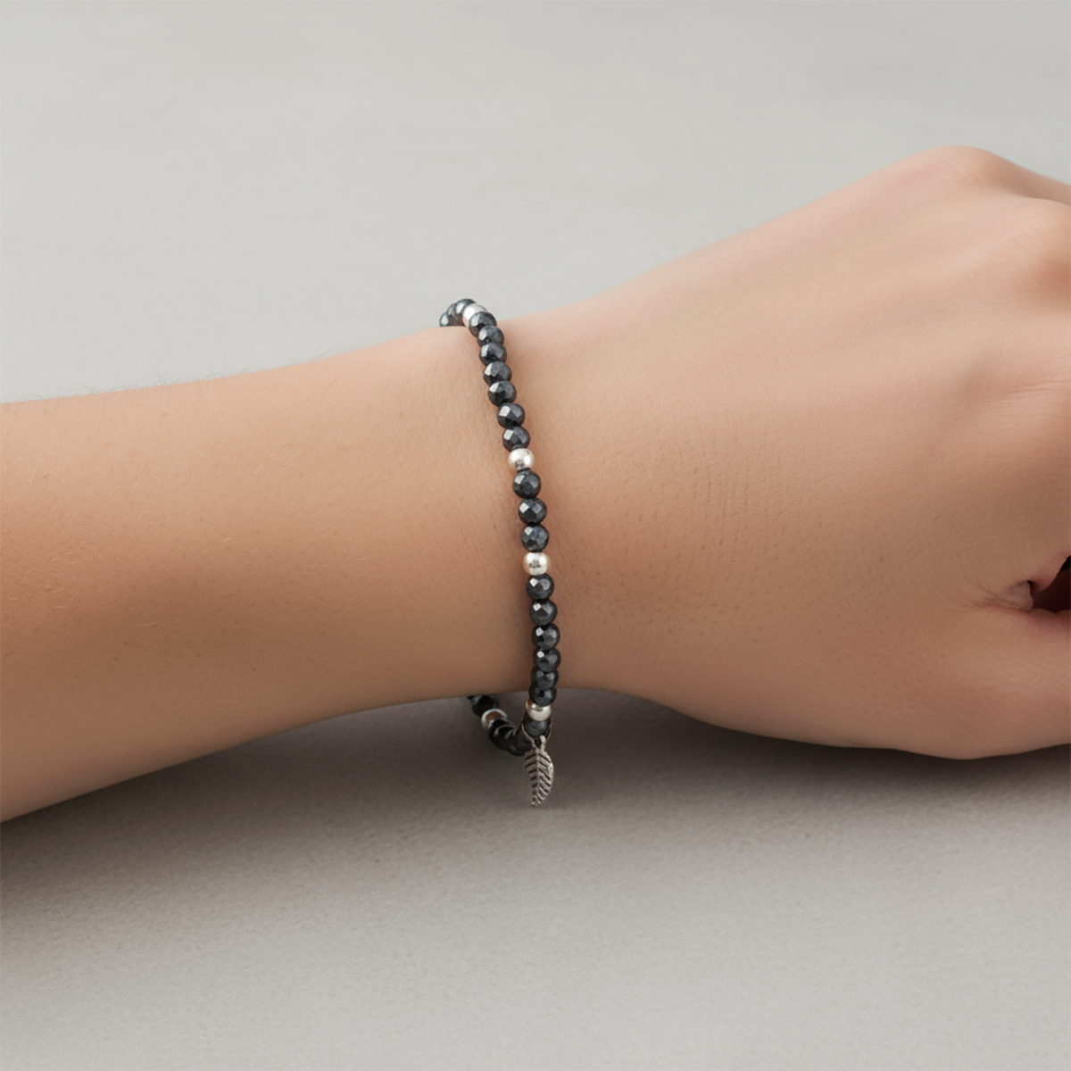 Black beaded bracelet on a wrist against a neutral background