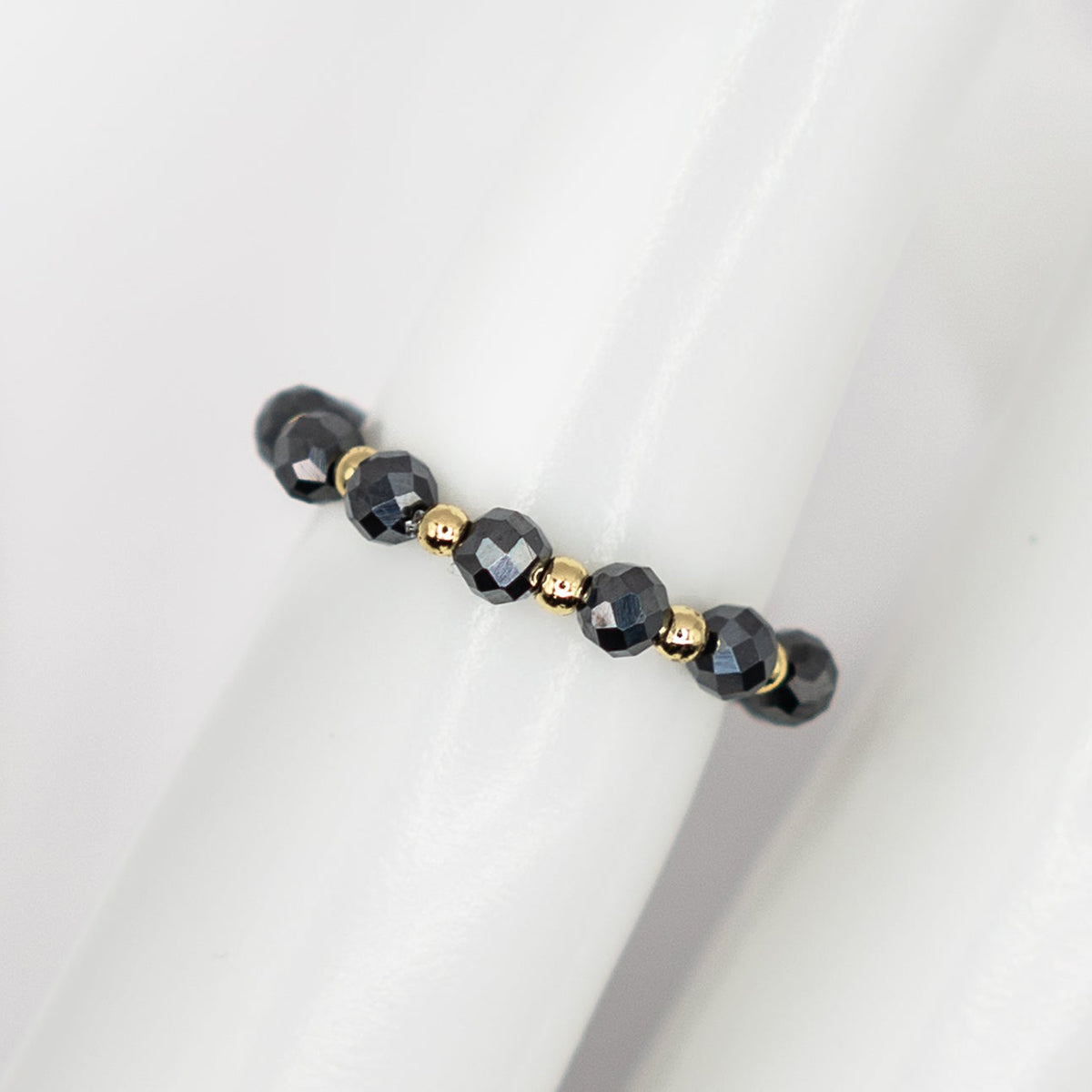Beaded bracelet with black and gold beads on a white background