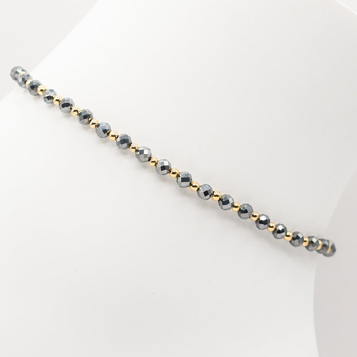 Beaded bracelet with alternating gold and silver beads on a white background