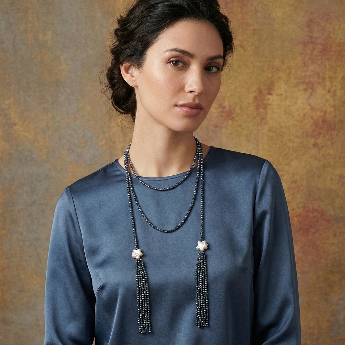 Woman wearing a long beaded necklace against a textured brown background