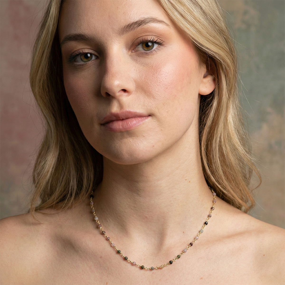 Woman wearing a delicate necklace against a neutral background