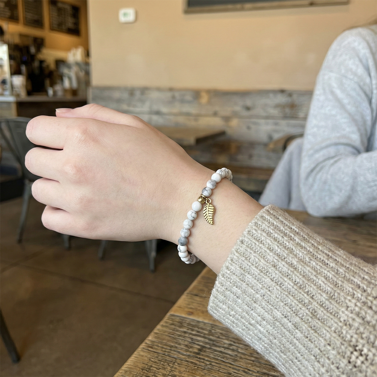 Person wearing a bracelet with a leaf charm in a casual setting