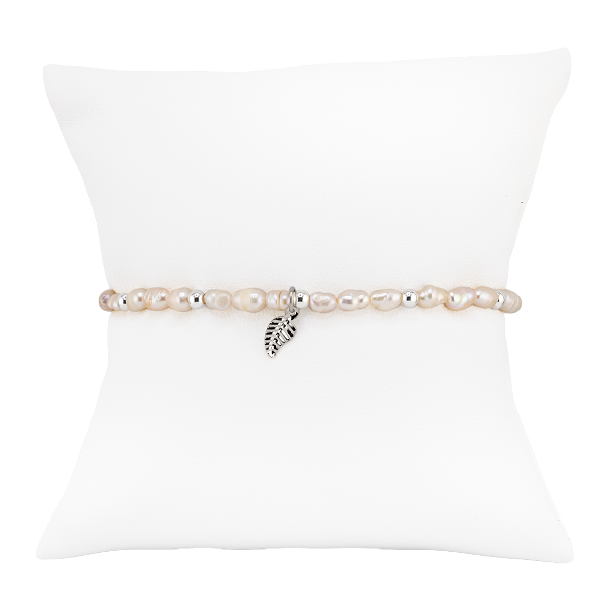 Pearl bracelet with a leaf charm on a white pillow