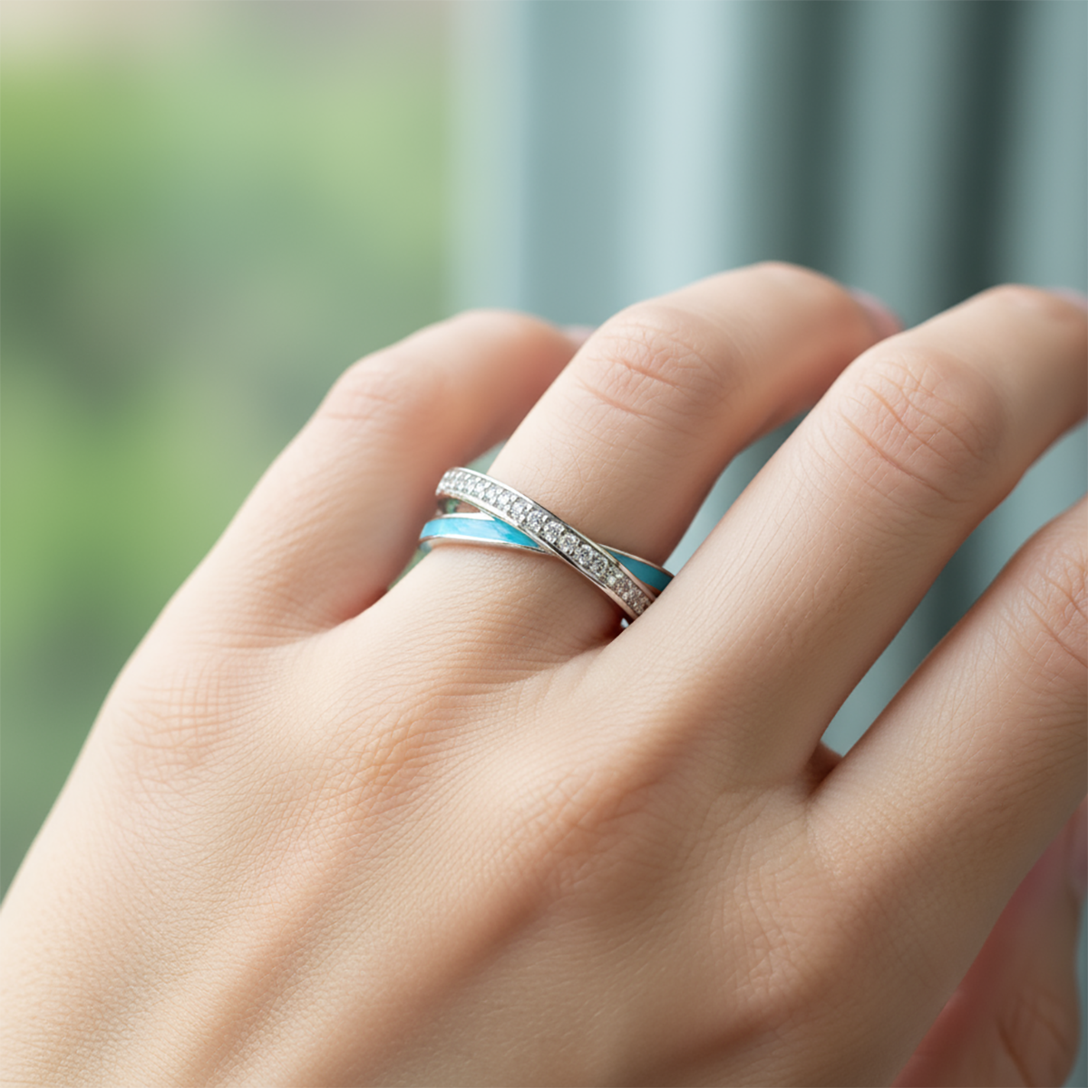 Hand wearing a ring with a blurred green and blue background