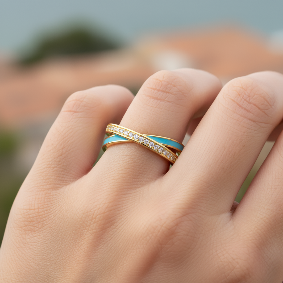 Close-up of a hand wearing a gold and blue ring with a blurred background