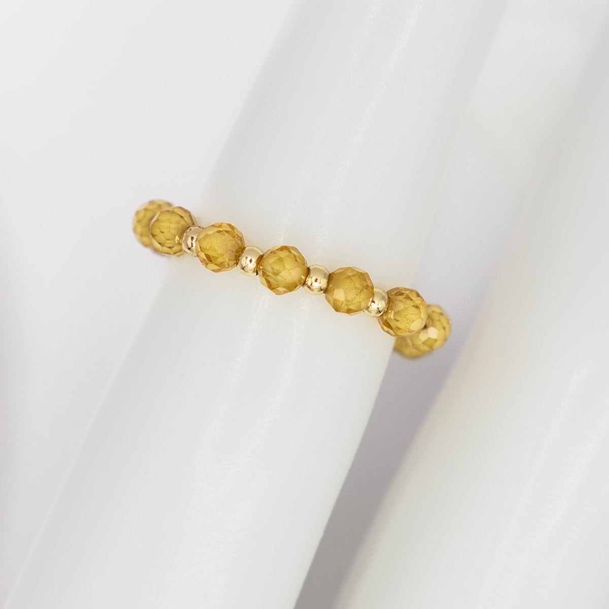 Gold bracelet with yellow beads on a white background