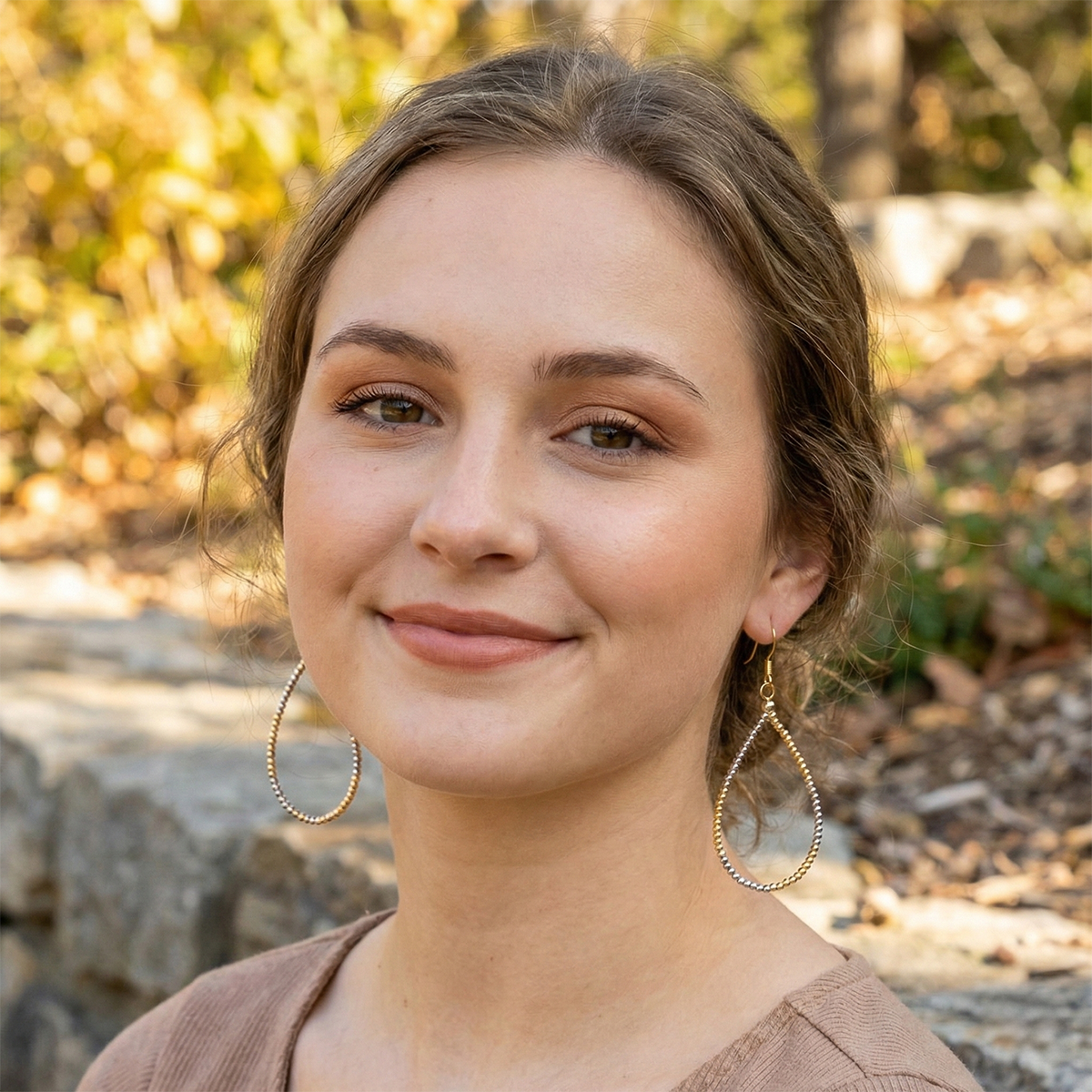 Woman with hoop earrings standing outdoors with a natural background