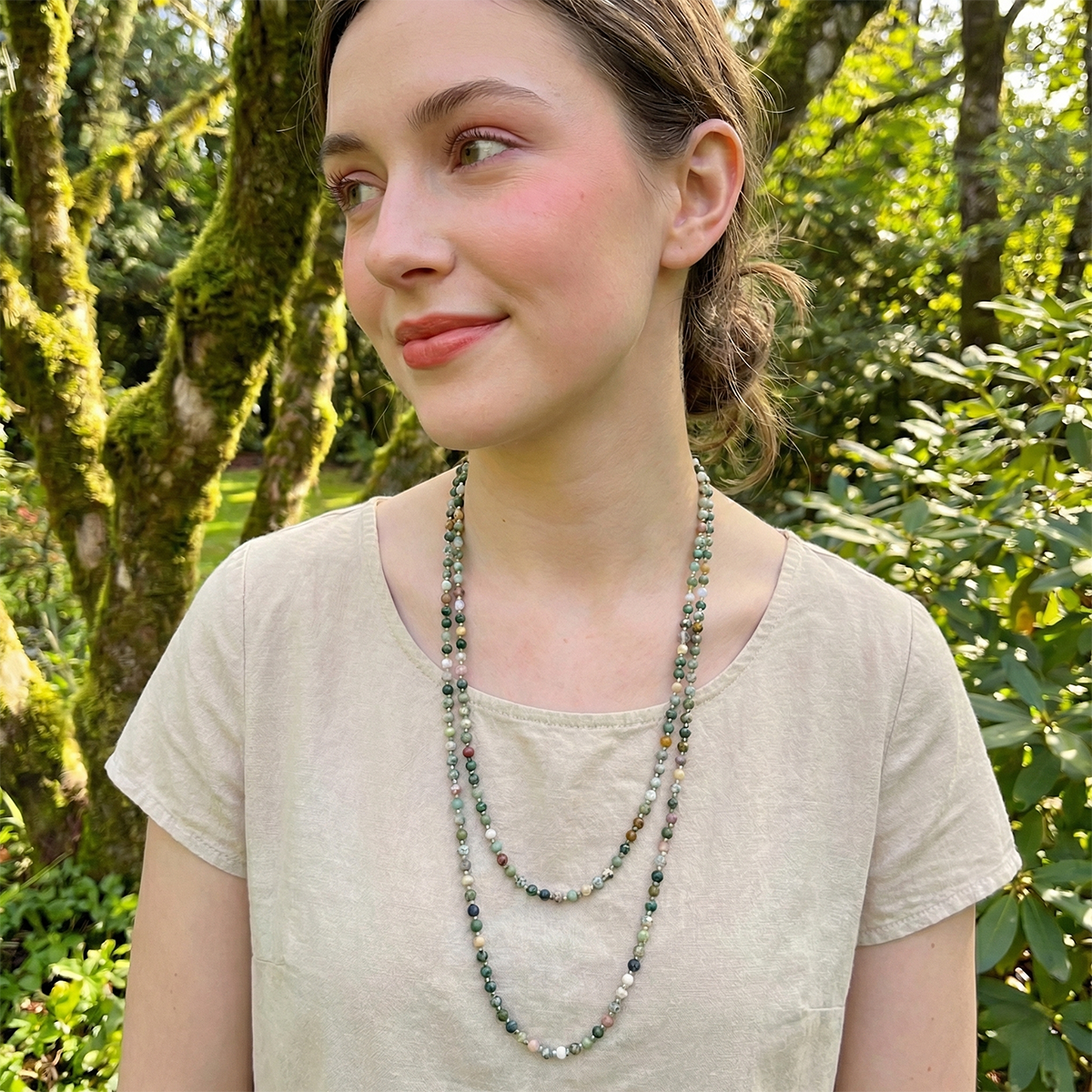 Woman wearing a beaded necklace in a forest setting