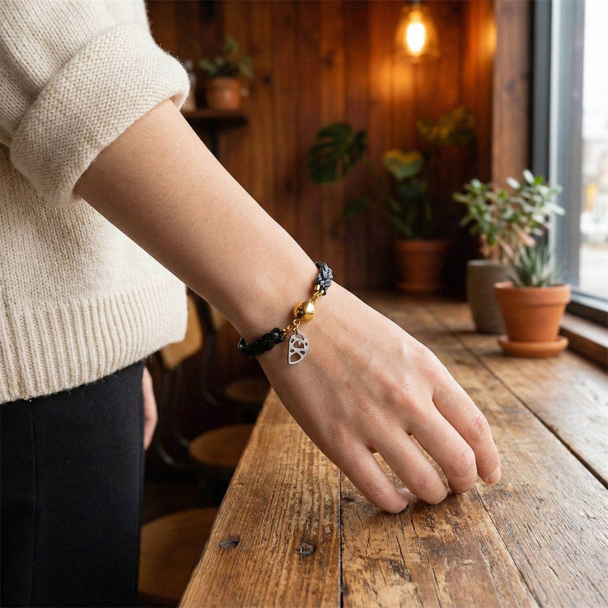 Person wearing a bracelet with charms on a wooden surface