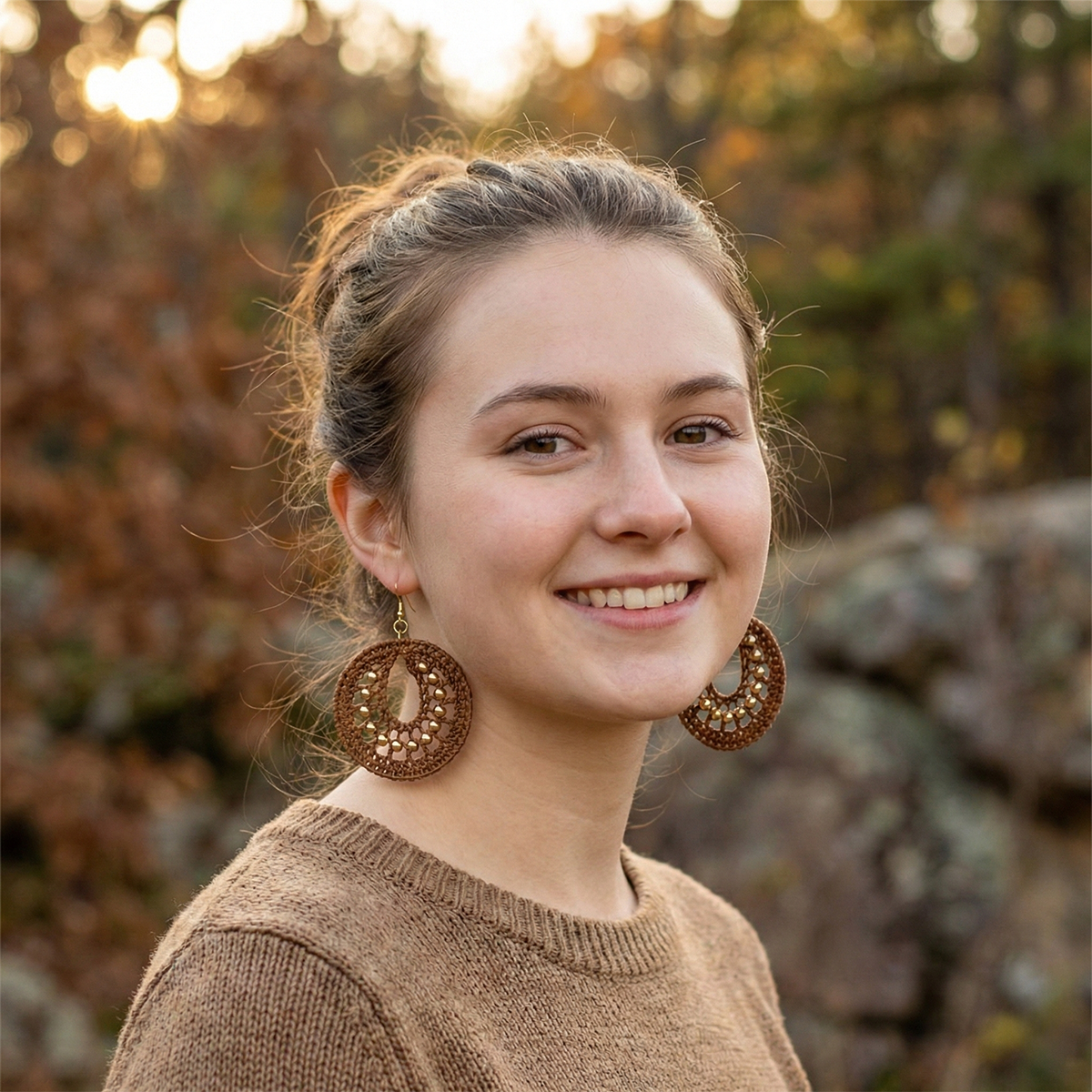Woman wearing large round earrings outdoors with a blurred natural background