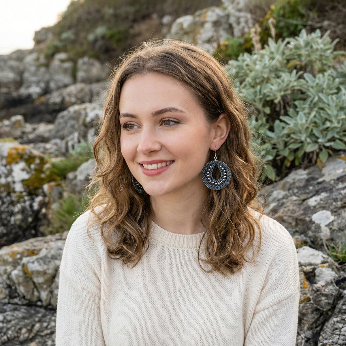 Woman with earrings standing in a rocky outdoor setting